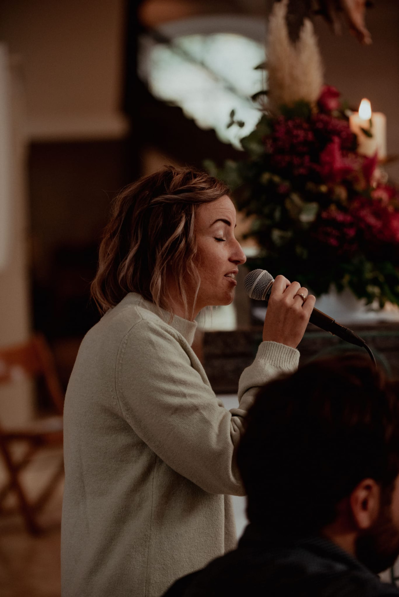 Lena Bruck singt bei einer Trauung mit Handmikrofon im warmen Kerzenlicht